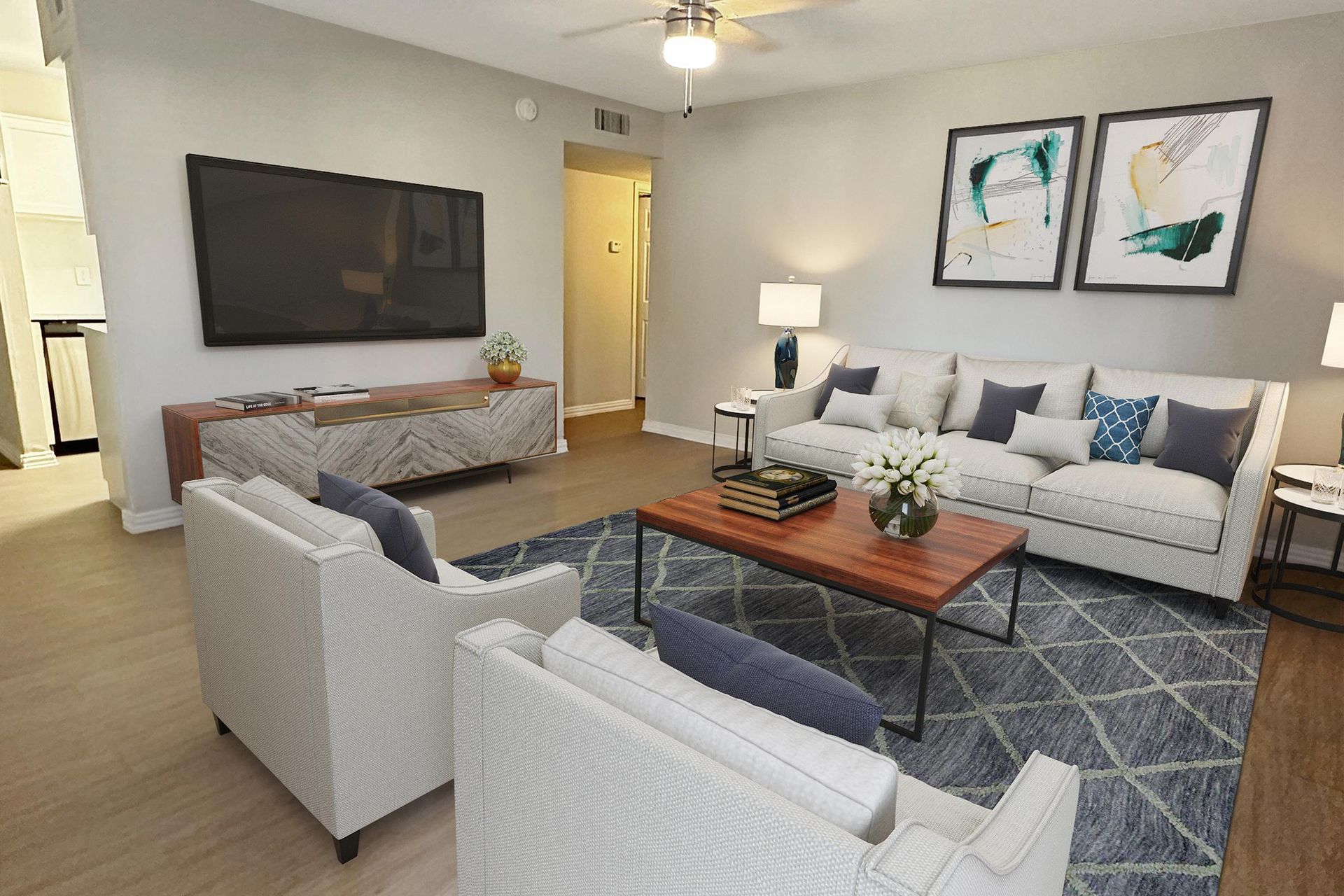 A living room with a couch , two chairs , a coffee table and a flat screen tv at Serena Apartment Homes.