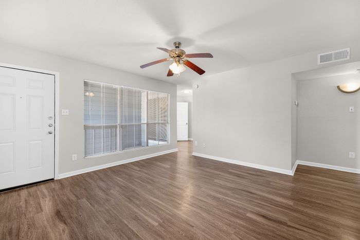 A living room with a red couch and a ceiling fan at Serena Apartment Homes.