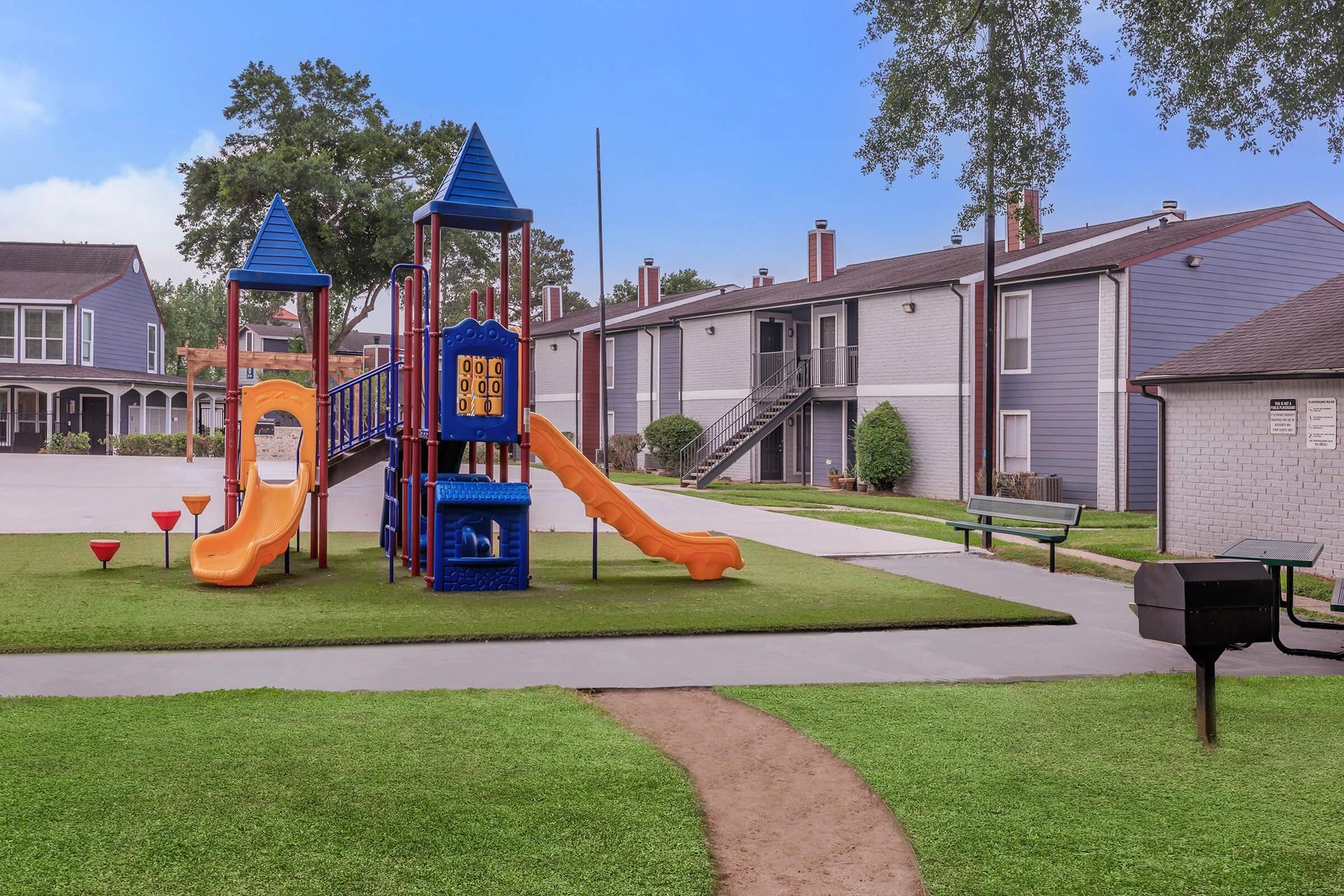 A playground with a slide and stairs in front of a building at Serena Apartment Homes.