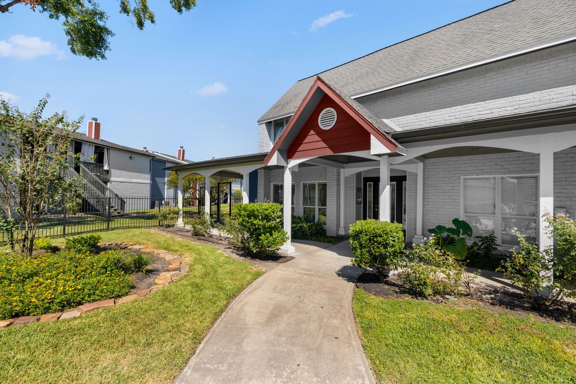 A large white house with a red roof and a walkway leading to the front door at Serena Apartment Homes. 