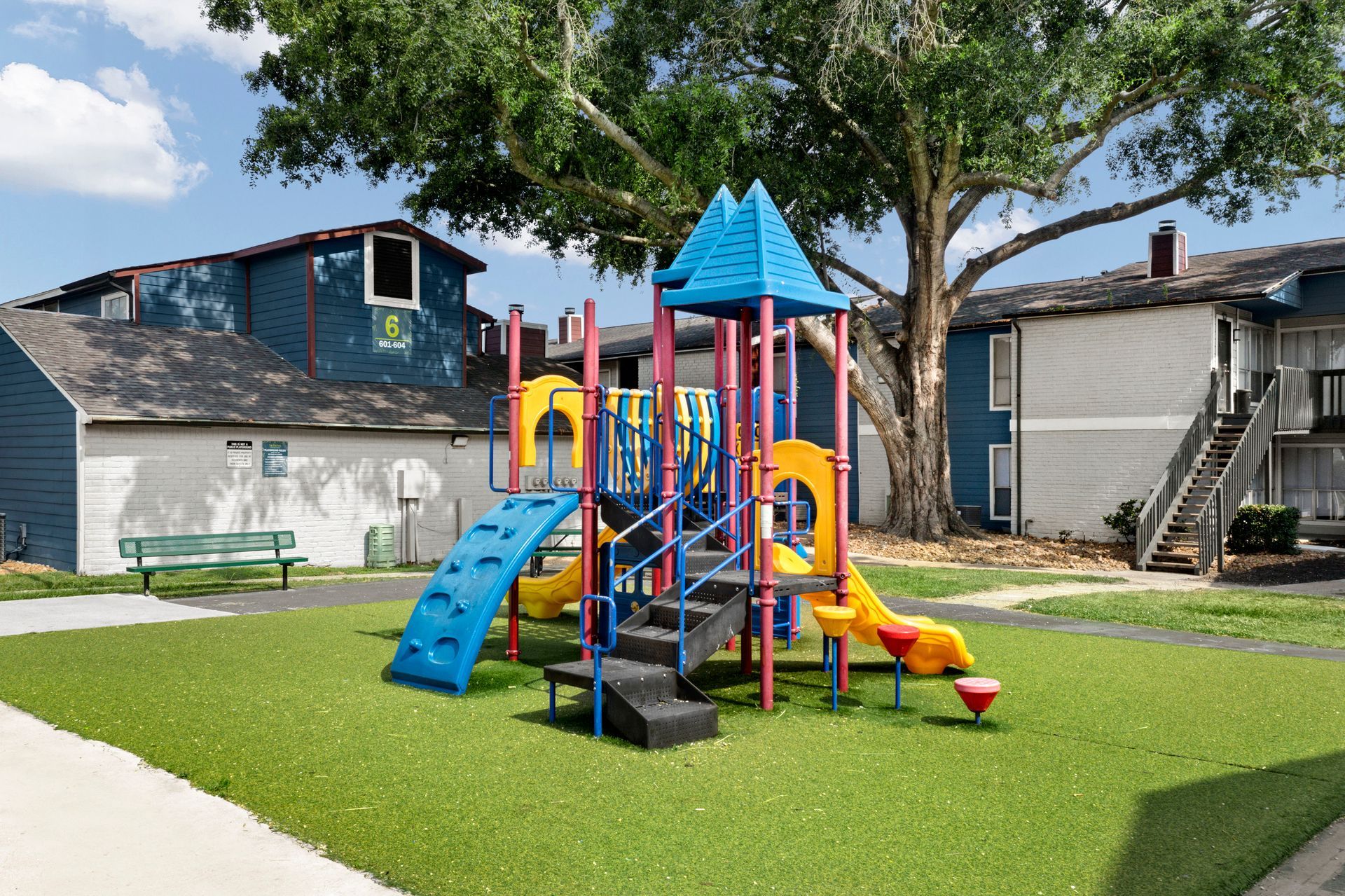 A playground with a slide and stairs in front of a building at Serena Apartment Homes.