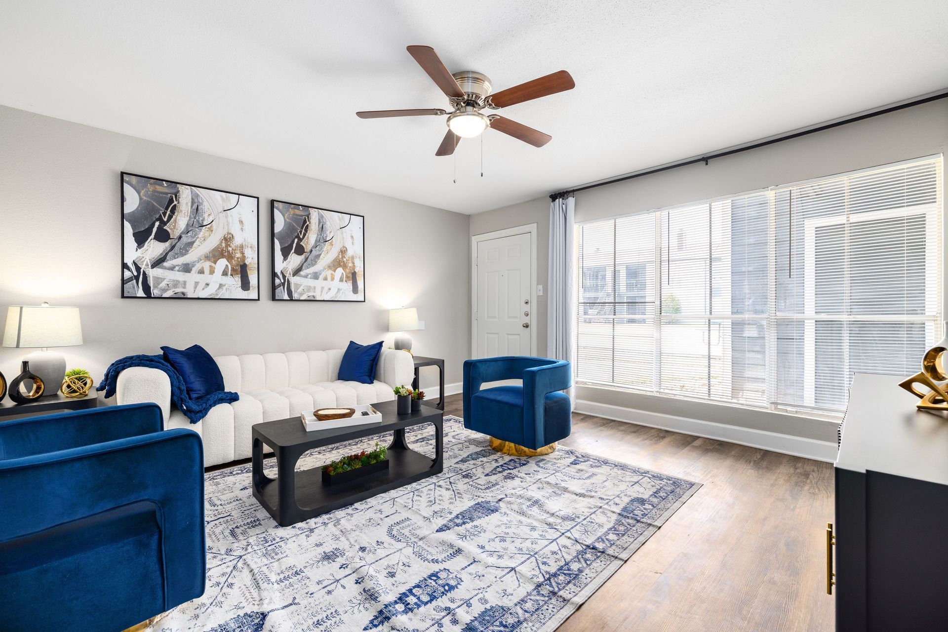 A living room with a couch , two chairs , a coffee table and a flat screen tv at Serena Apartment Homes.