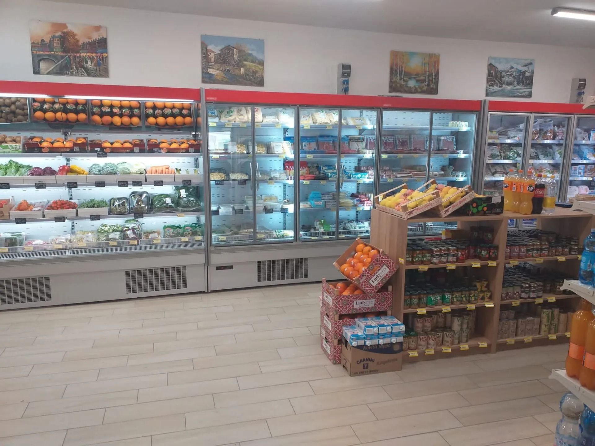 Corsie dedicate alla frutta e verdura in un supermercato, con scaffali refrigerati e un espositore in legno.