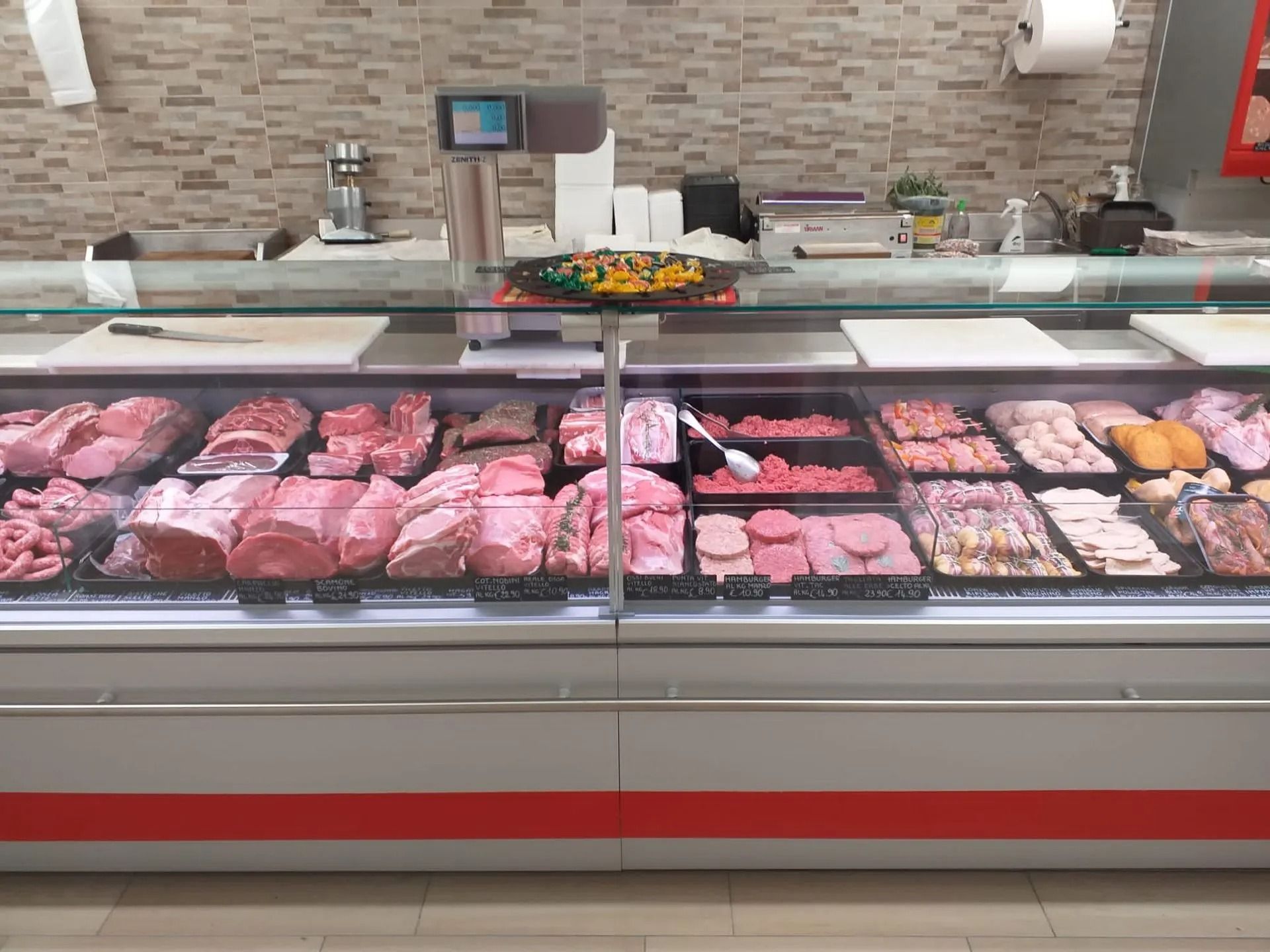 Una vetrina in un negozio di alimentari piena di vari tagli di carne cruda, tra cui bistecche, costolette e hamburger.