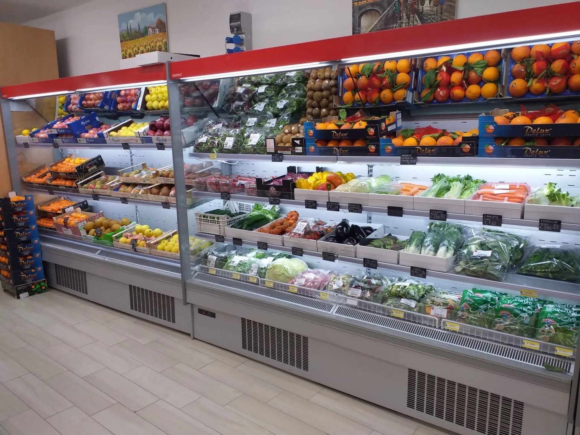 Un banco frigo per alimenti, pieno di un'ampia varietà di frutta e verdura fresca, in un negozio al dettaglio.