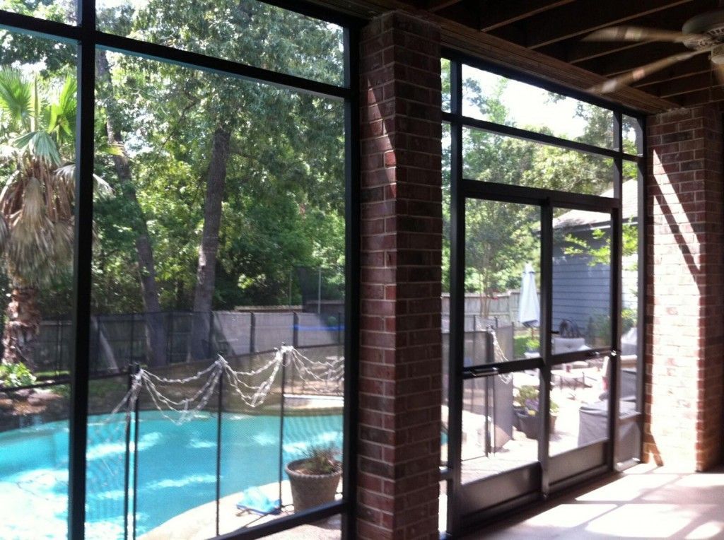 A screened in porch with a swimming pool in the background