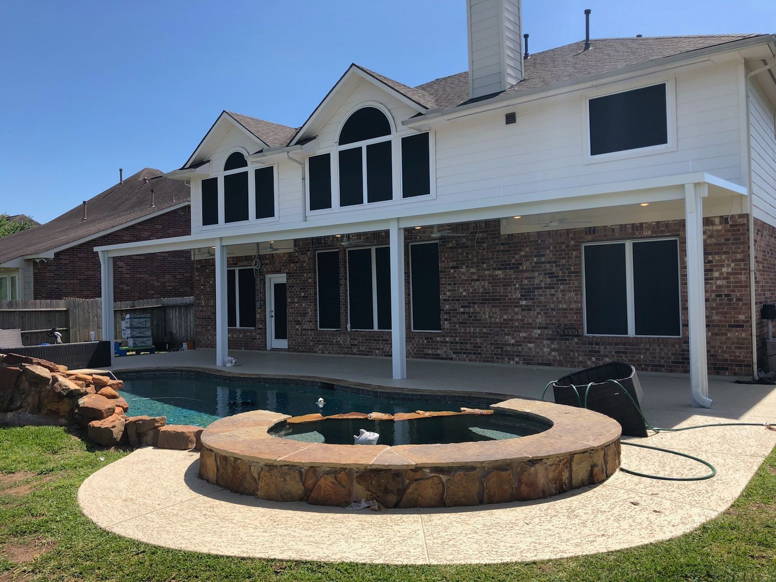 A large house with a covered deck, swimming pool and a hot tub in front of it in Taylor, TX.