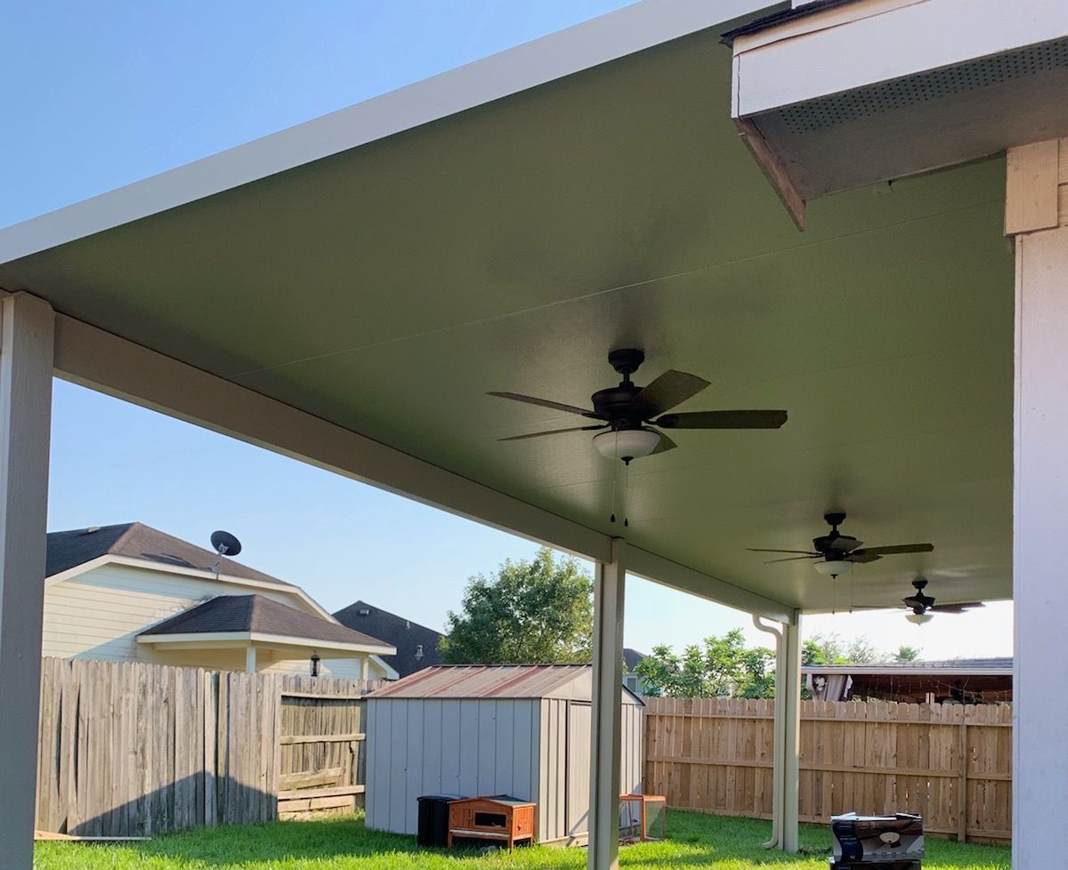 a covered patio with a ceiling fan in the backyard of a house.
