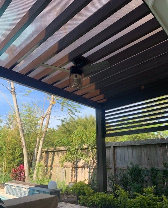 A ceiling fan is hanging from the roof of a shaded patio structure in Bee Cave, TX.