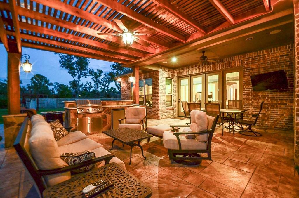 A cedar pergola patio in Buda, TX with a couch , chairs , tables and a ceiling fan.