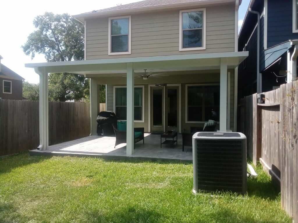 A backyard patio with a covered shade structure, creating an outdoor dining area.