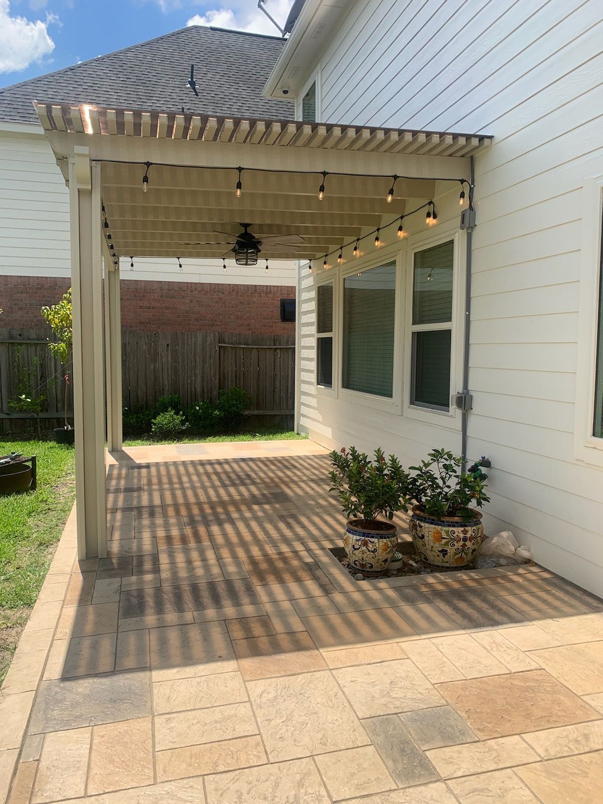 a patio with a pergola and potted plants underneath it