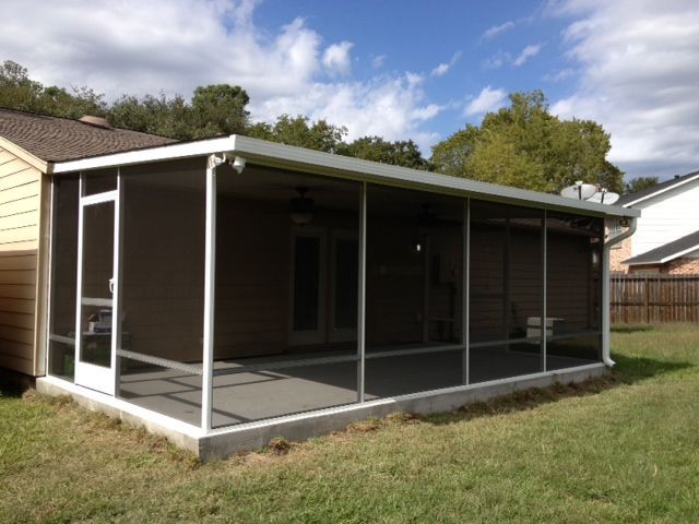 A screen enclosure attached to the back of a customers home near me in Katy, TX with a concrete slab.