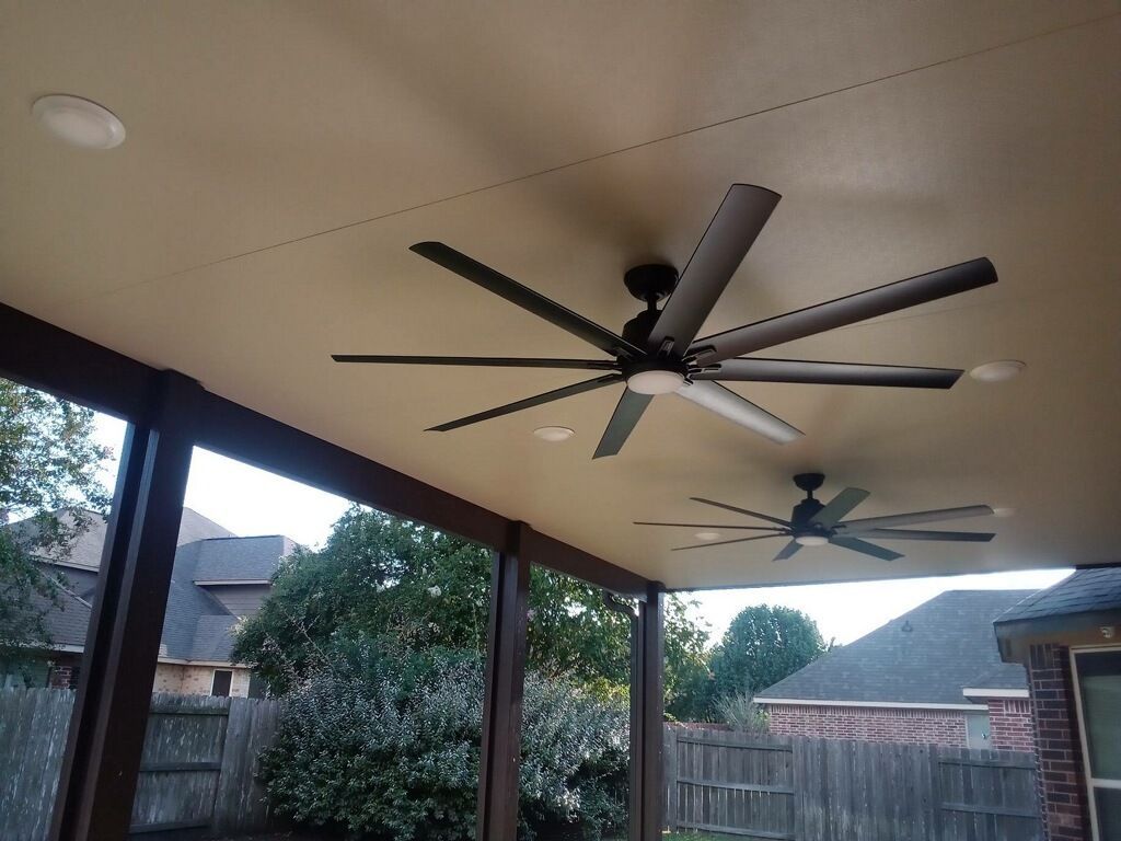 Two ceiling fans are hanging from the ceiling of a screened in porch.