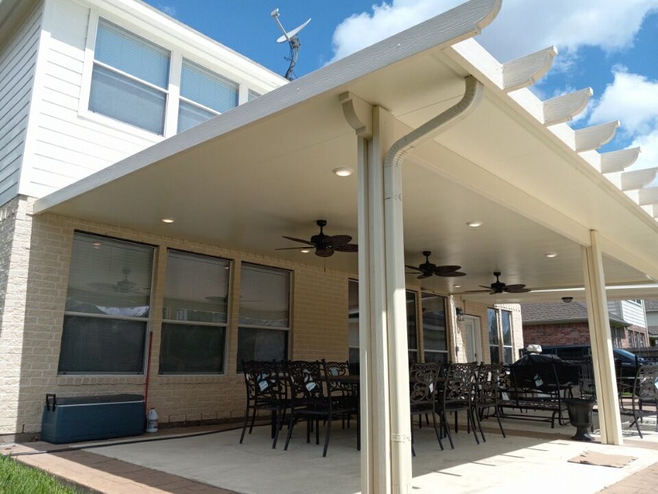 there is an aluminum patio cover with a ceiling fan and chairs underneath it.