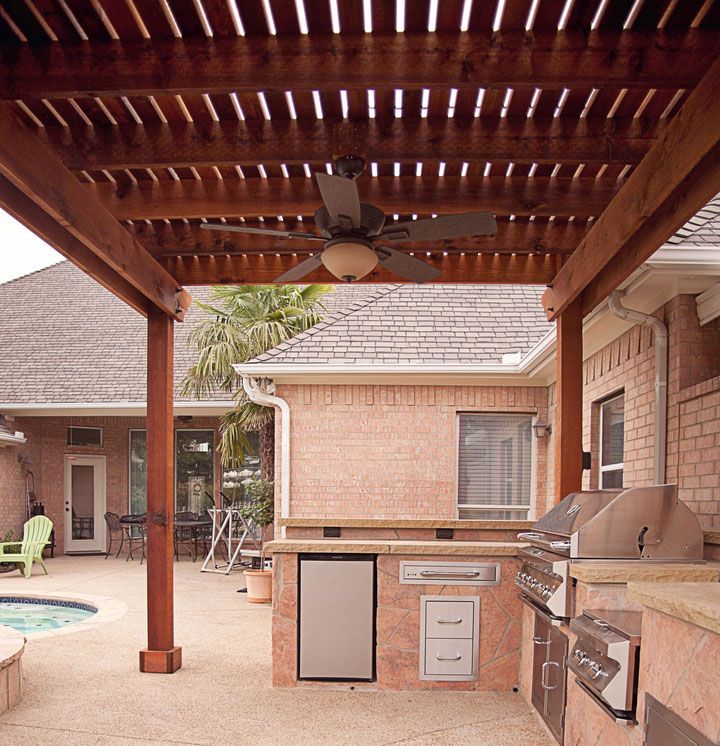 a brick house with a wooden pergola and a ceiling fan