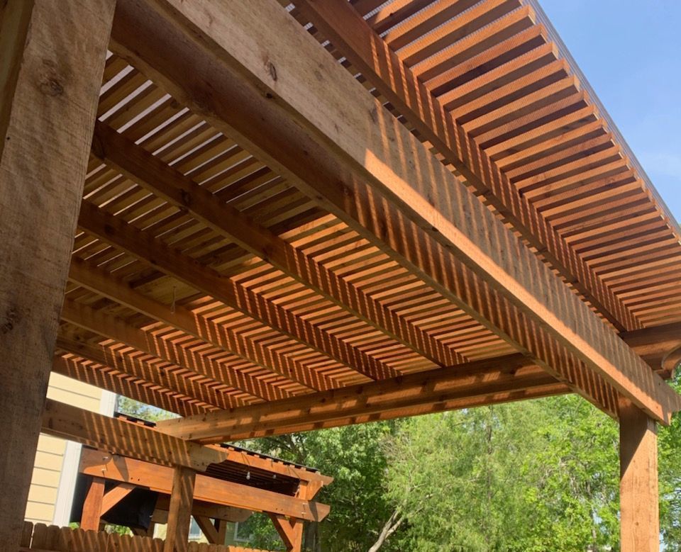 a close up of a wooden pergola with a blue sky in the background