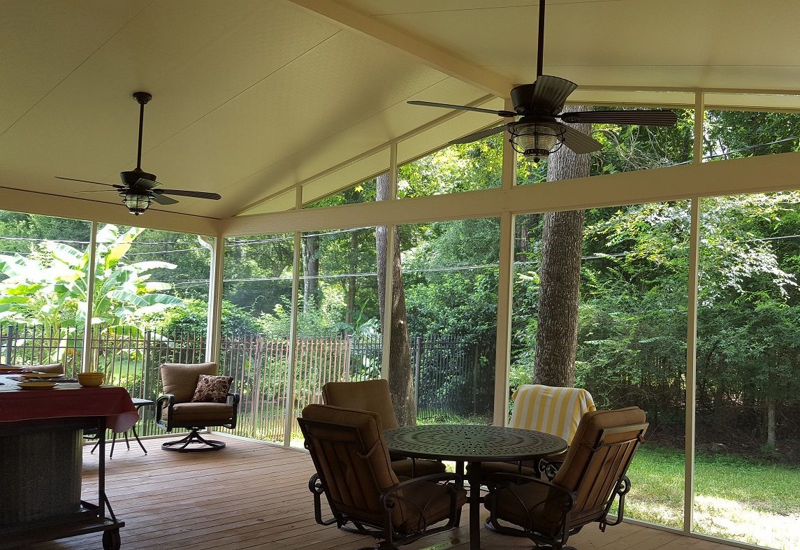 a screened in porch with a table and chairs and a ceiling fan