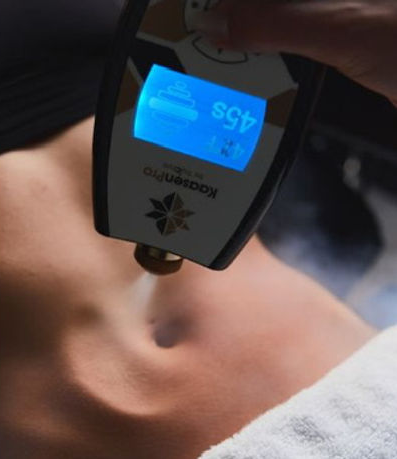 Woman receiving a cryotherapy treatment on her neck and chest. A technician holds the device, with visible mist and laser.