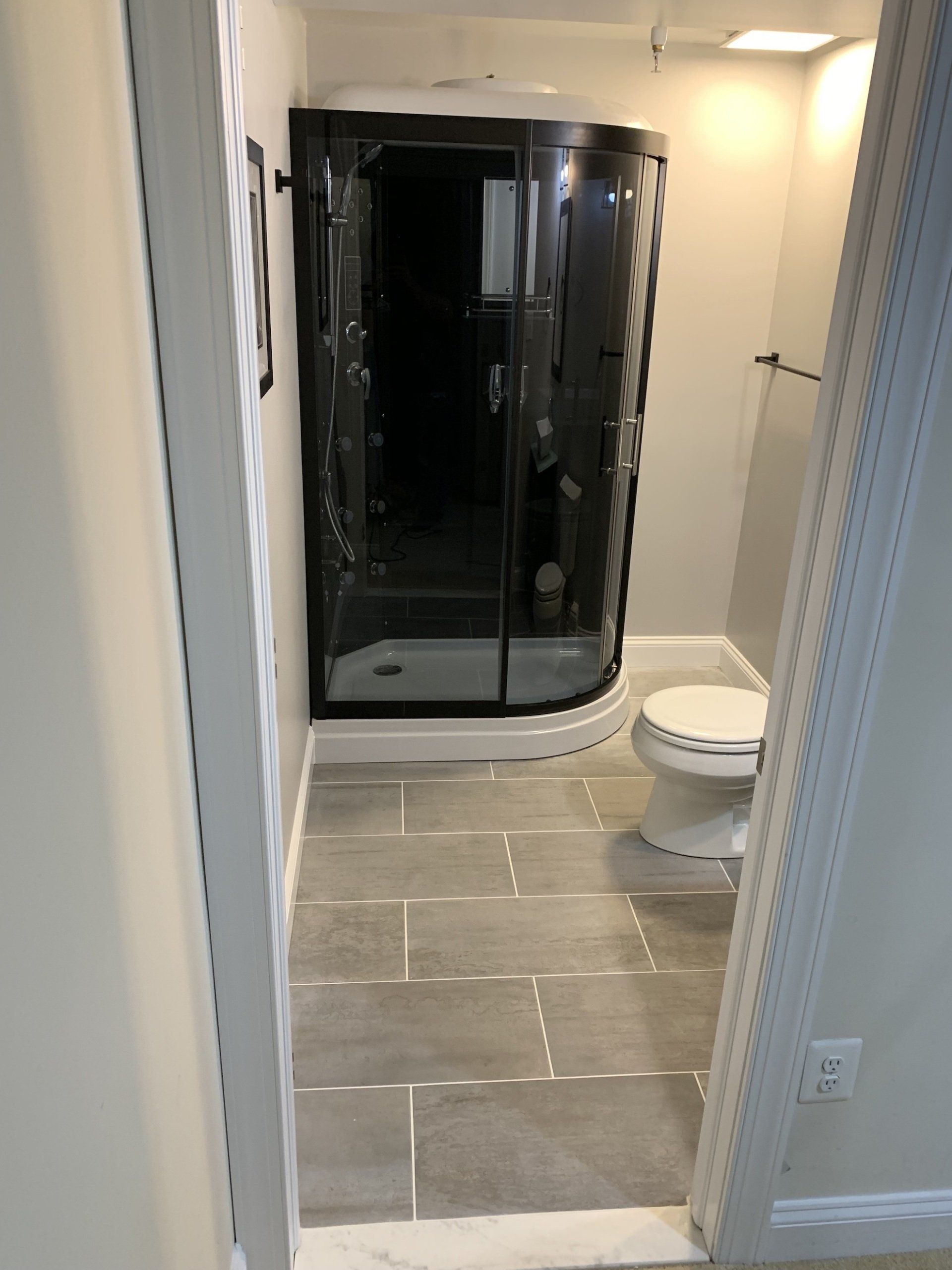 bathroom renovation with rounded glass shower enclosure and tiled floors
