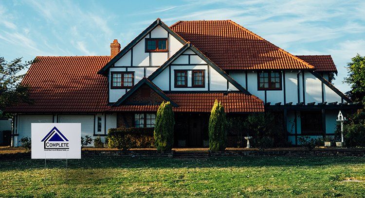 A large house with a for sale sign in front of it.