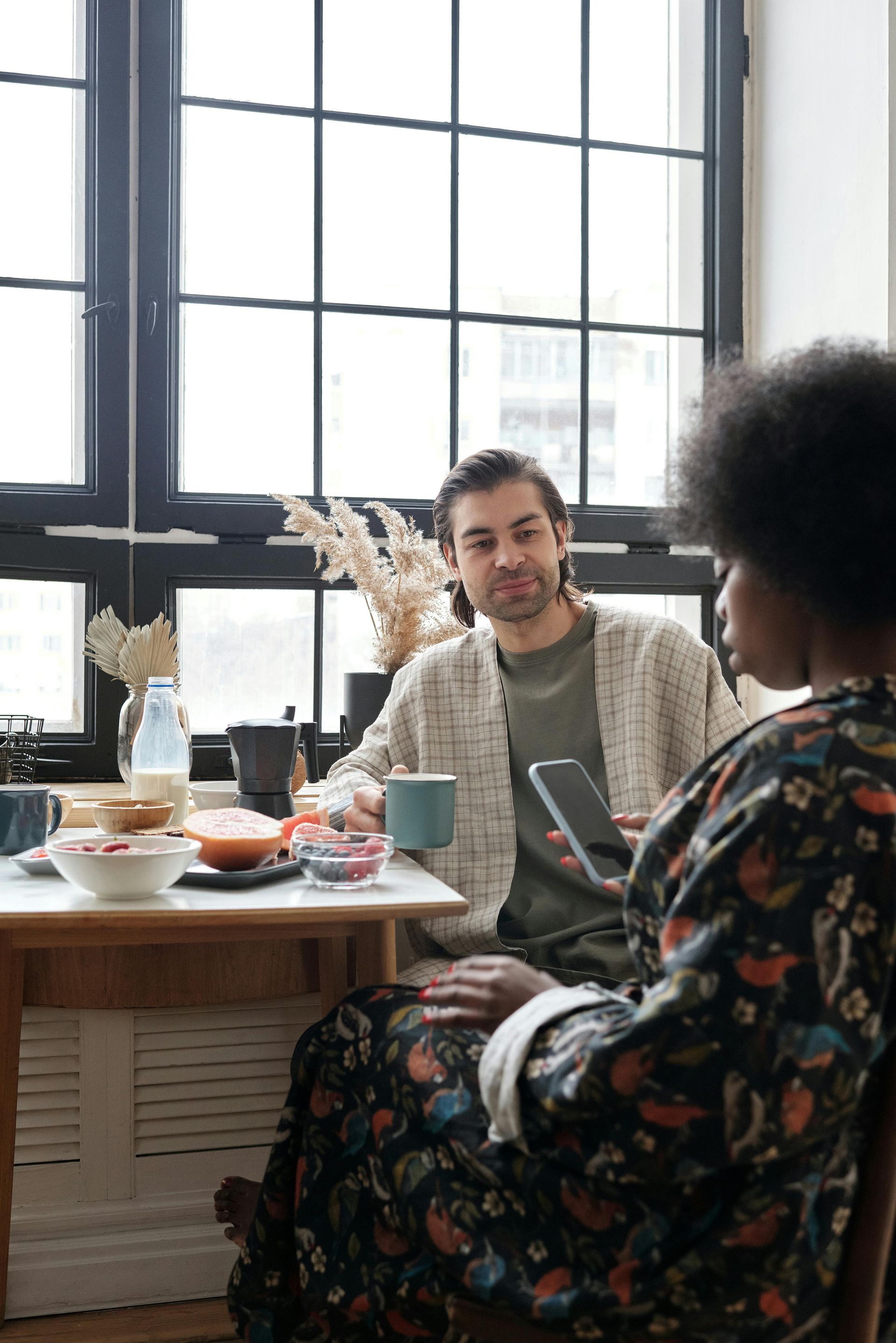 A man and a woman are sitting at a table talking to each other.