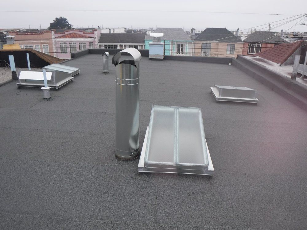 Skylight on a gray shingle roof. The window is rectangular with a dark frame.