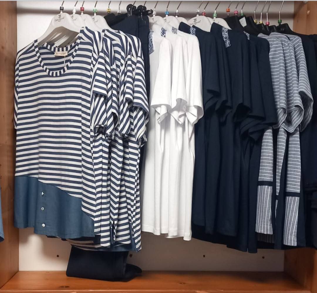 Un negozio pieno di vestiti appesi sugli scaffali.