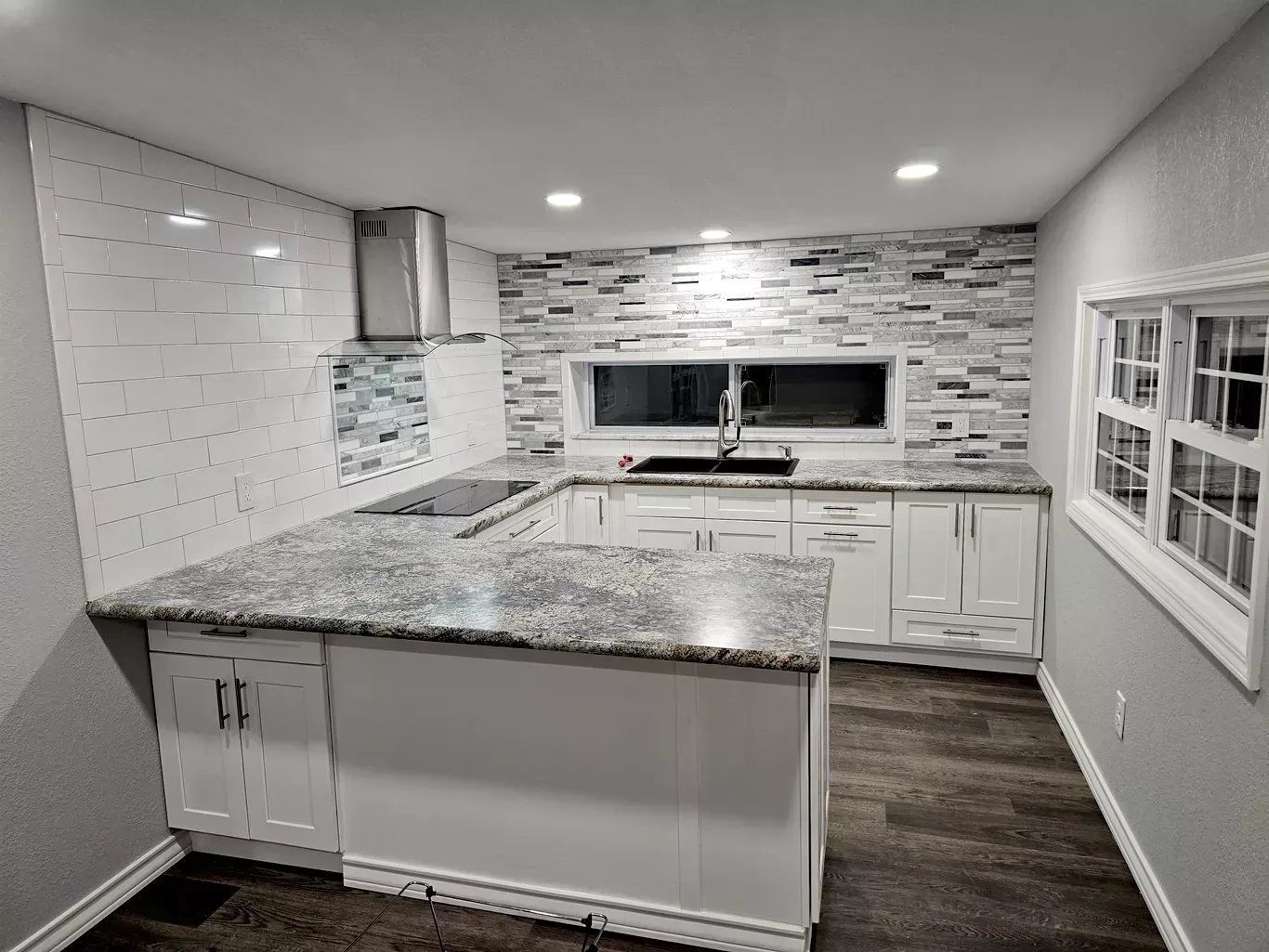 Modern kitchen with white cabinets, gray granite countertops, and patterned backsplash.
