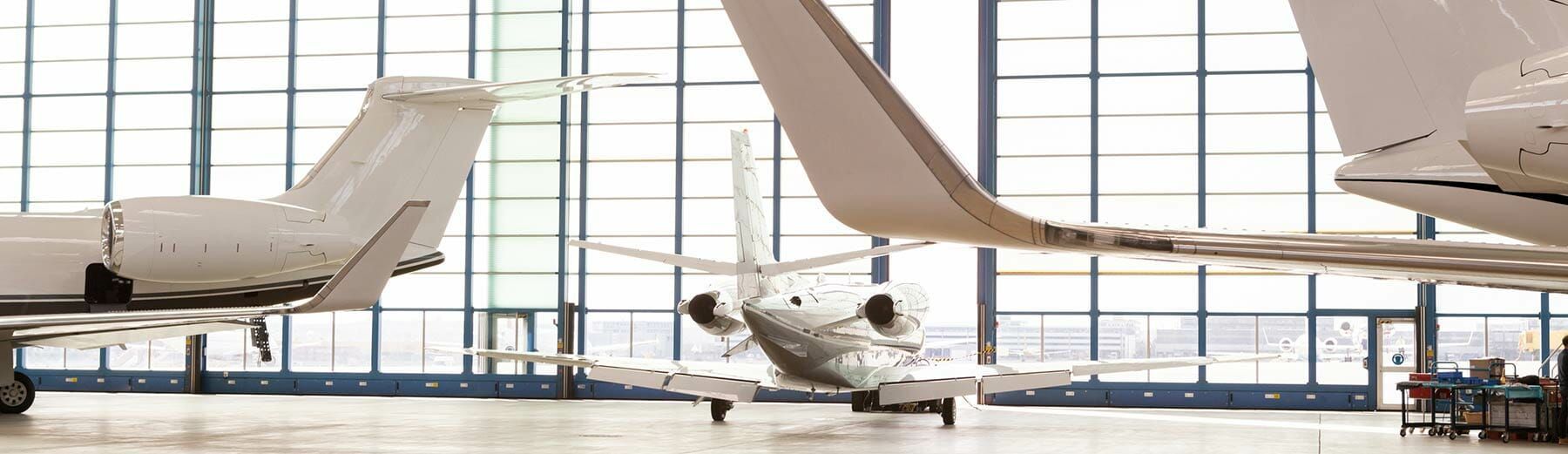 Three private jets are parked in a hangar.