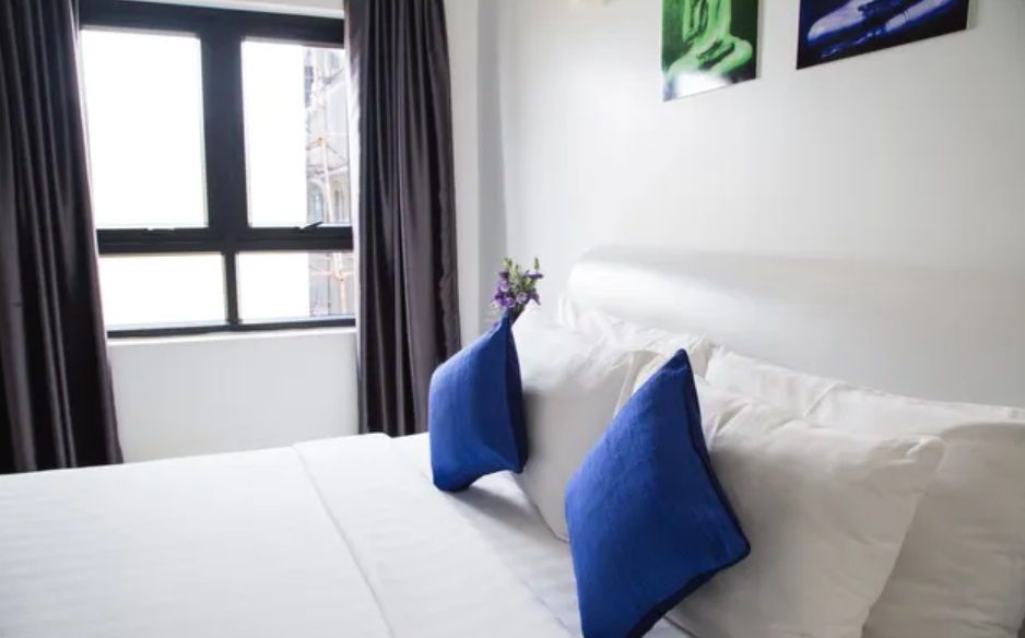 a bed with white sheets and blue pillows in a photo taken by photoholic