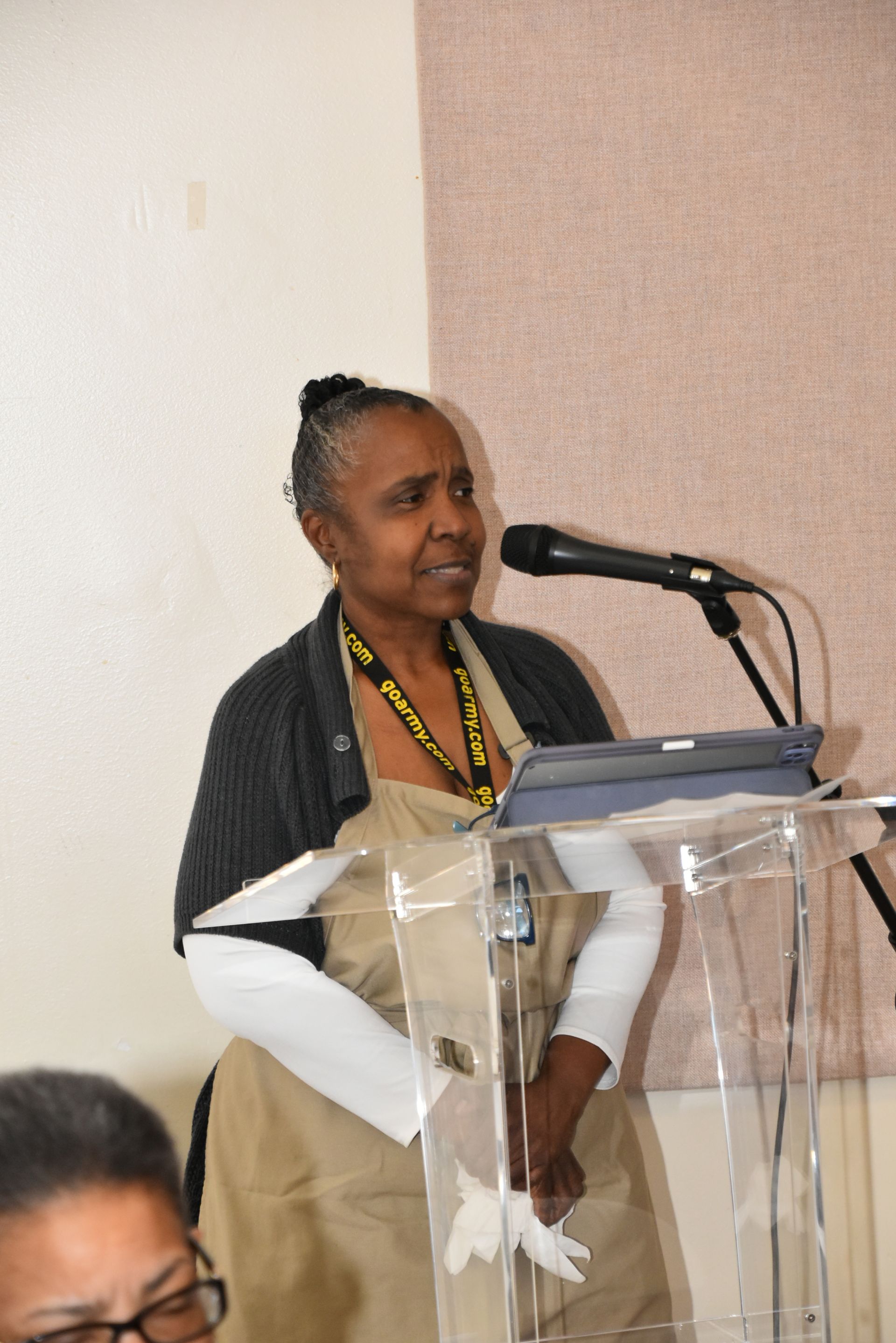 A woman is standing at a podium speaking into a microphone.