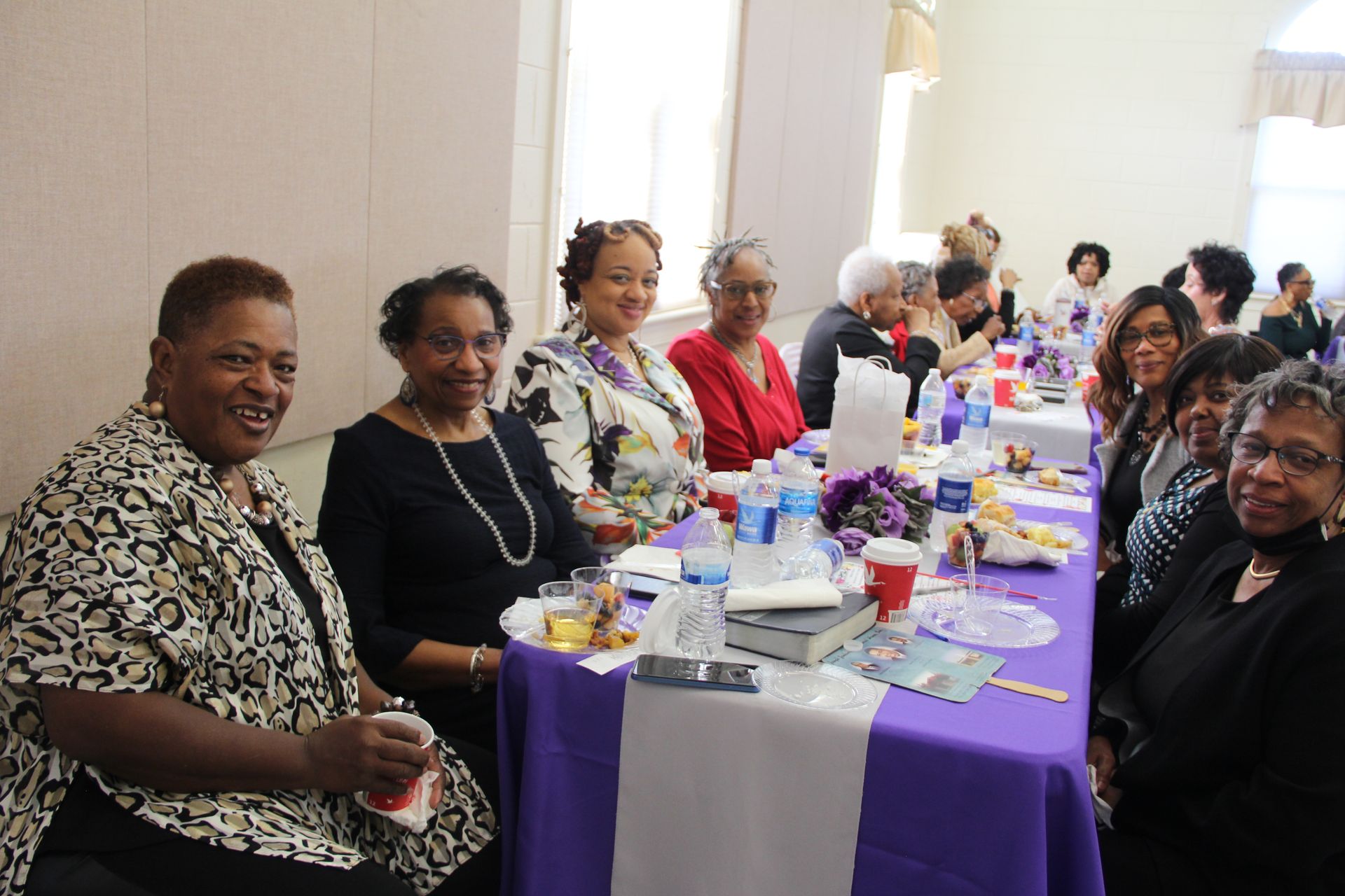 A group of women are sitting at a long table.