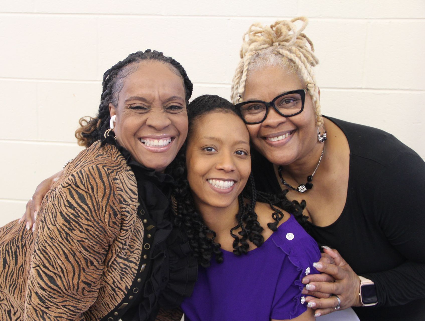 Three women are posing for a picture together and smiling for the camera.