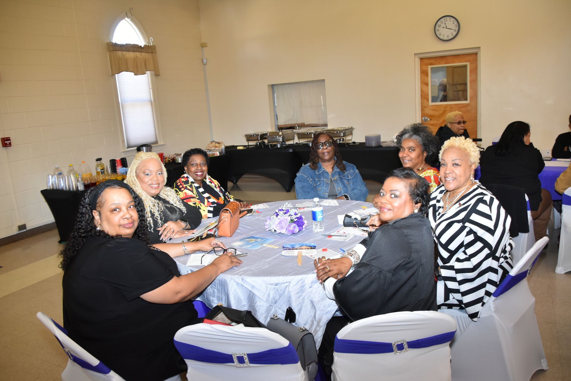 A group of women are sitting around a table in a room.
