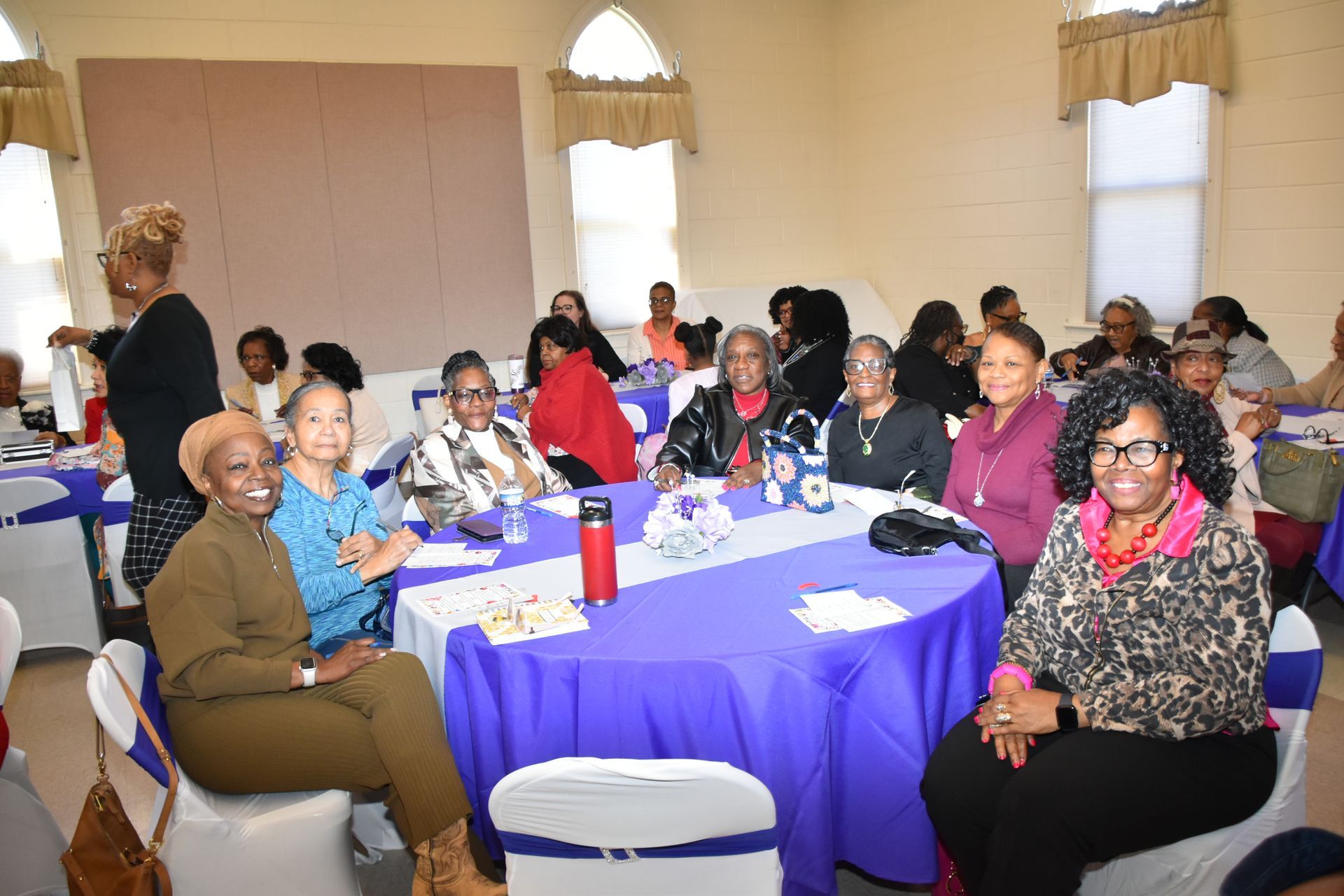 A group of women are sitting at tables in a room.