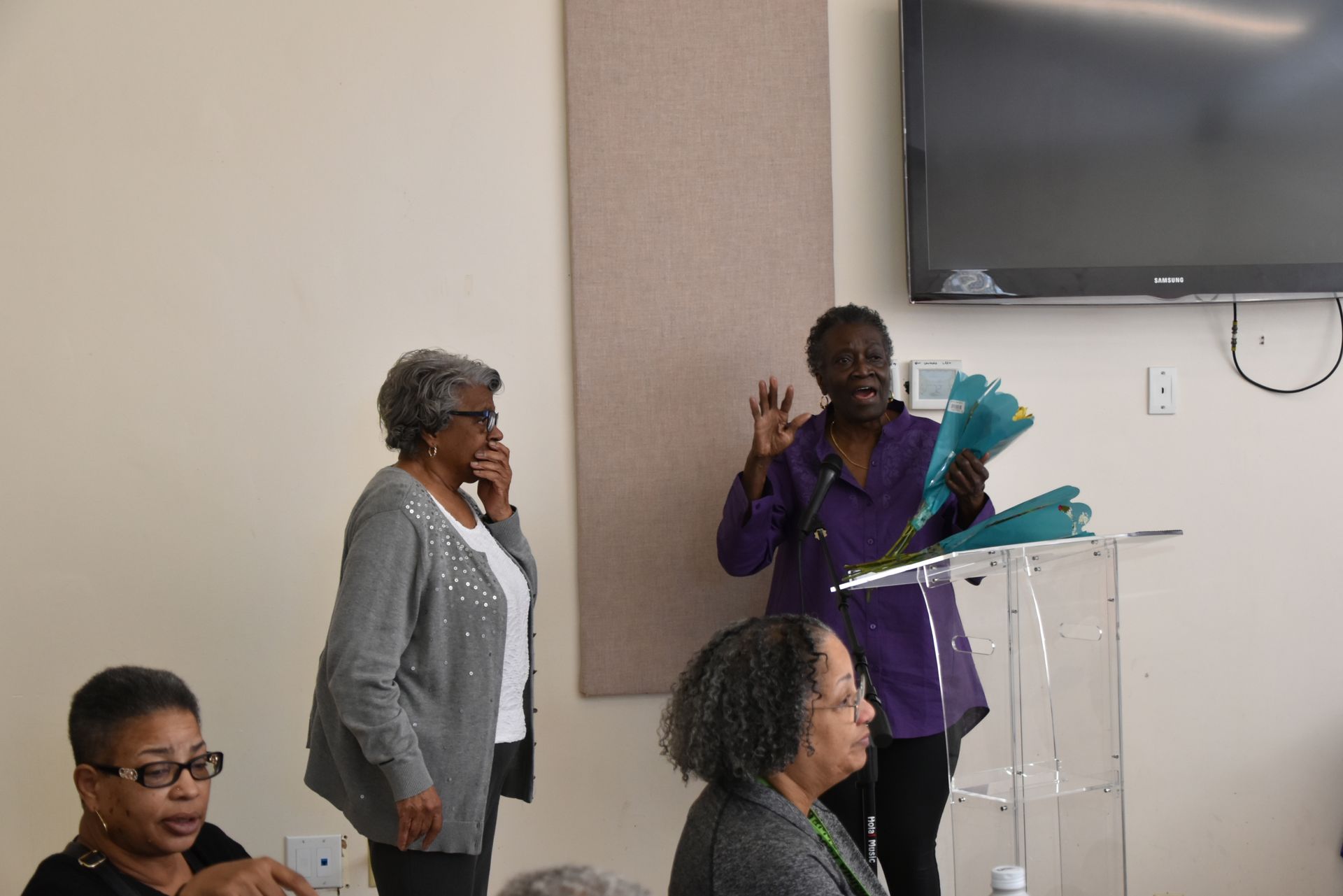 A woman is standing at a podium giving a presentation to a group of people.