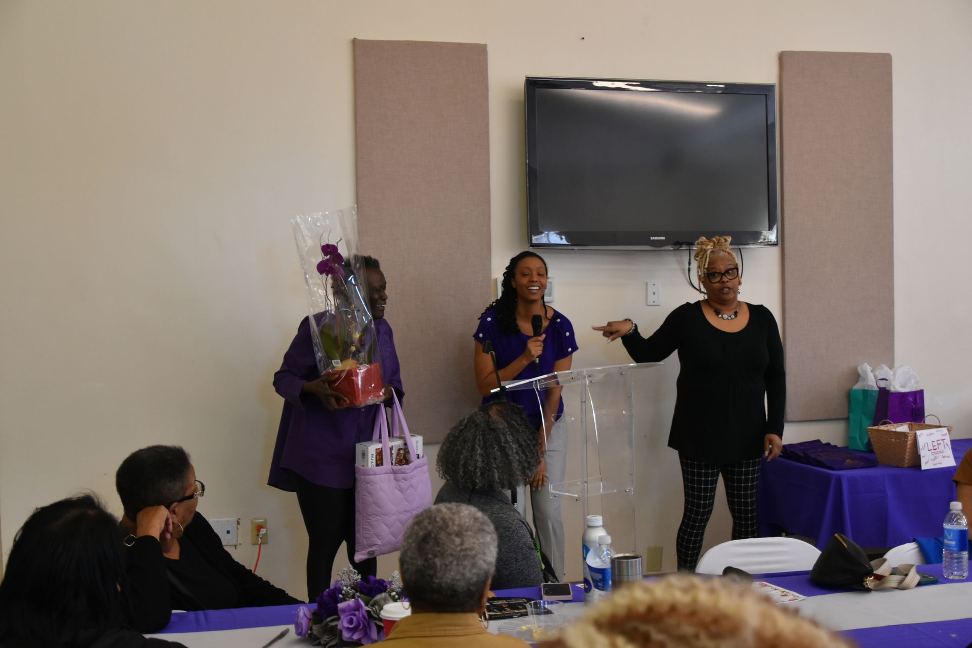 A group of people are sitting at a table in front of a television.