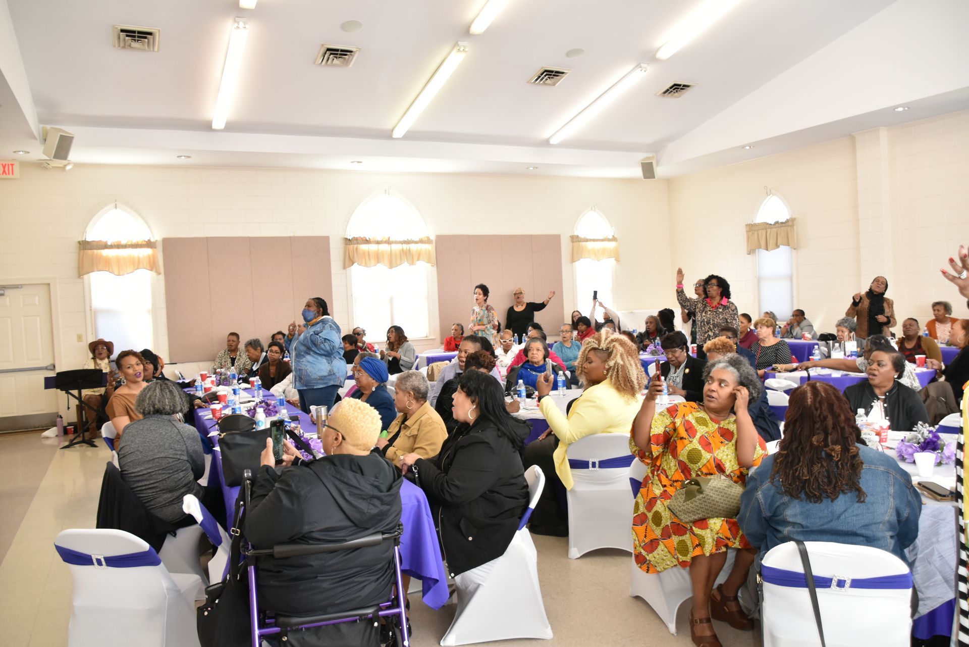 A large group of people are sitting at tables in a large room.