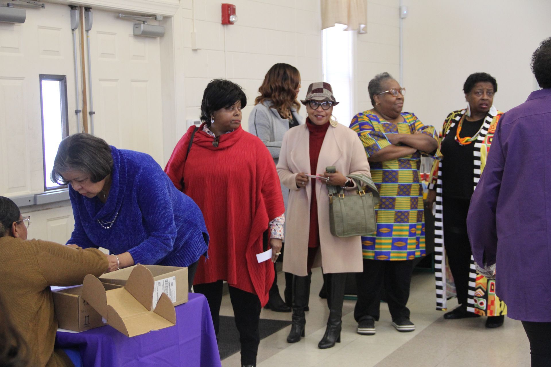 A group of women are standing around a table in a room.