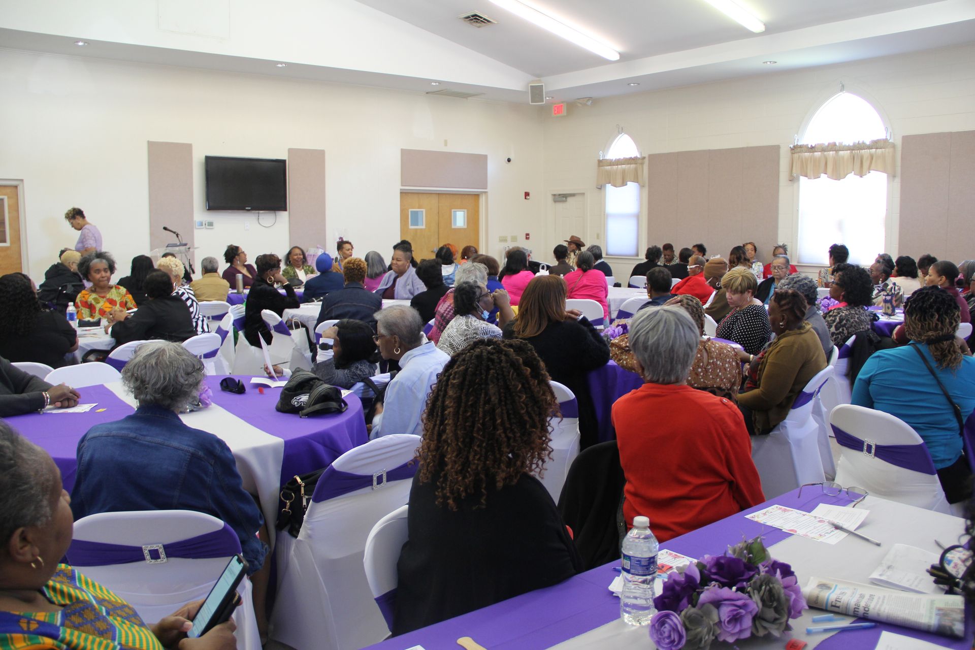 A large group of people are sitting at tables in a room.