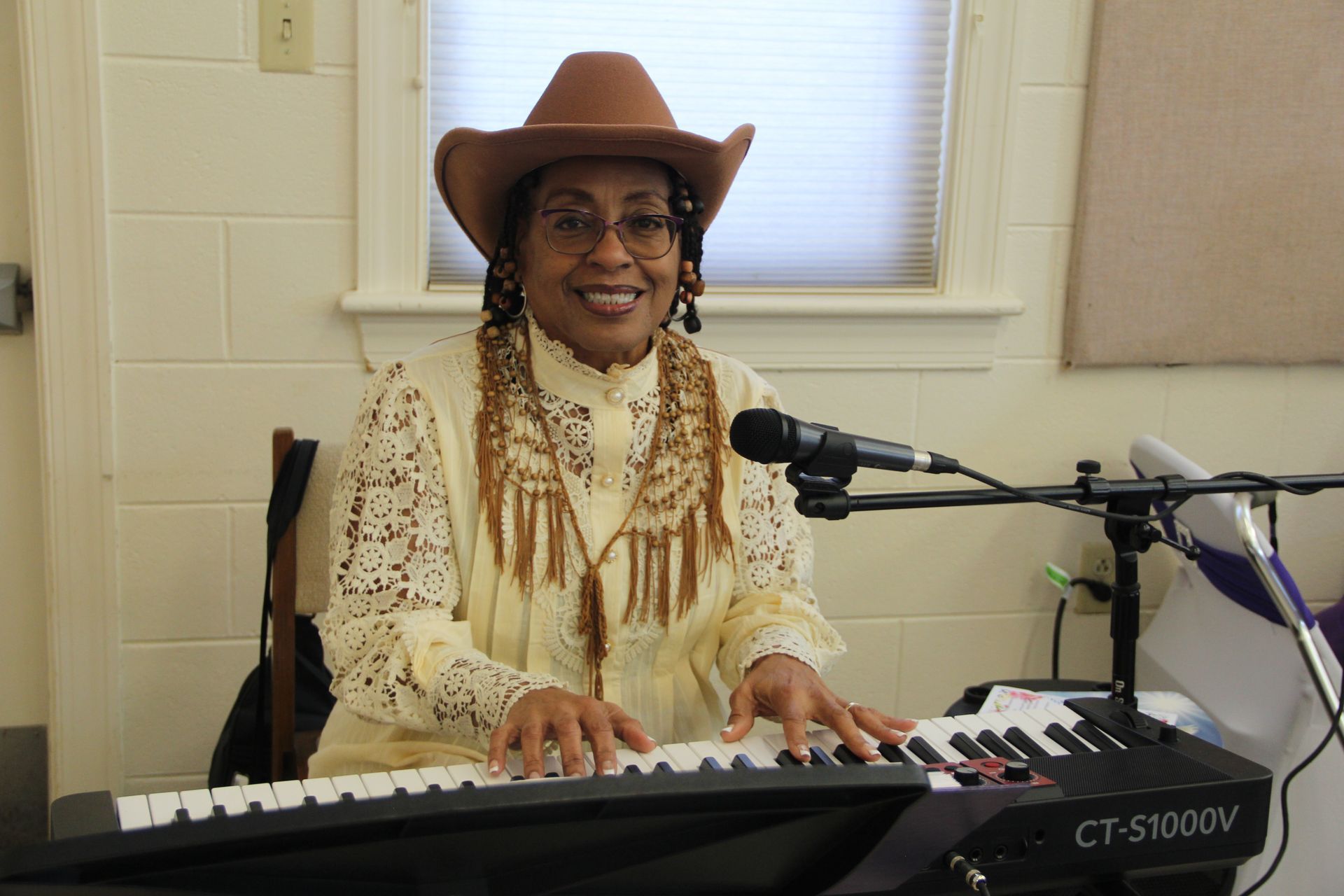 A woman wearing a cowboy hat is playing a keyboard