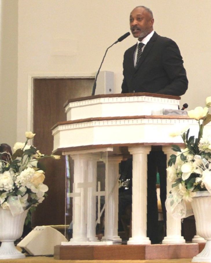 Pastor in a suit and tie giving a speech at a podium