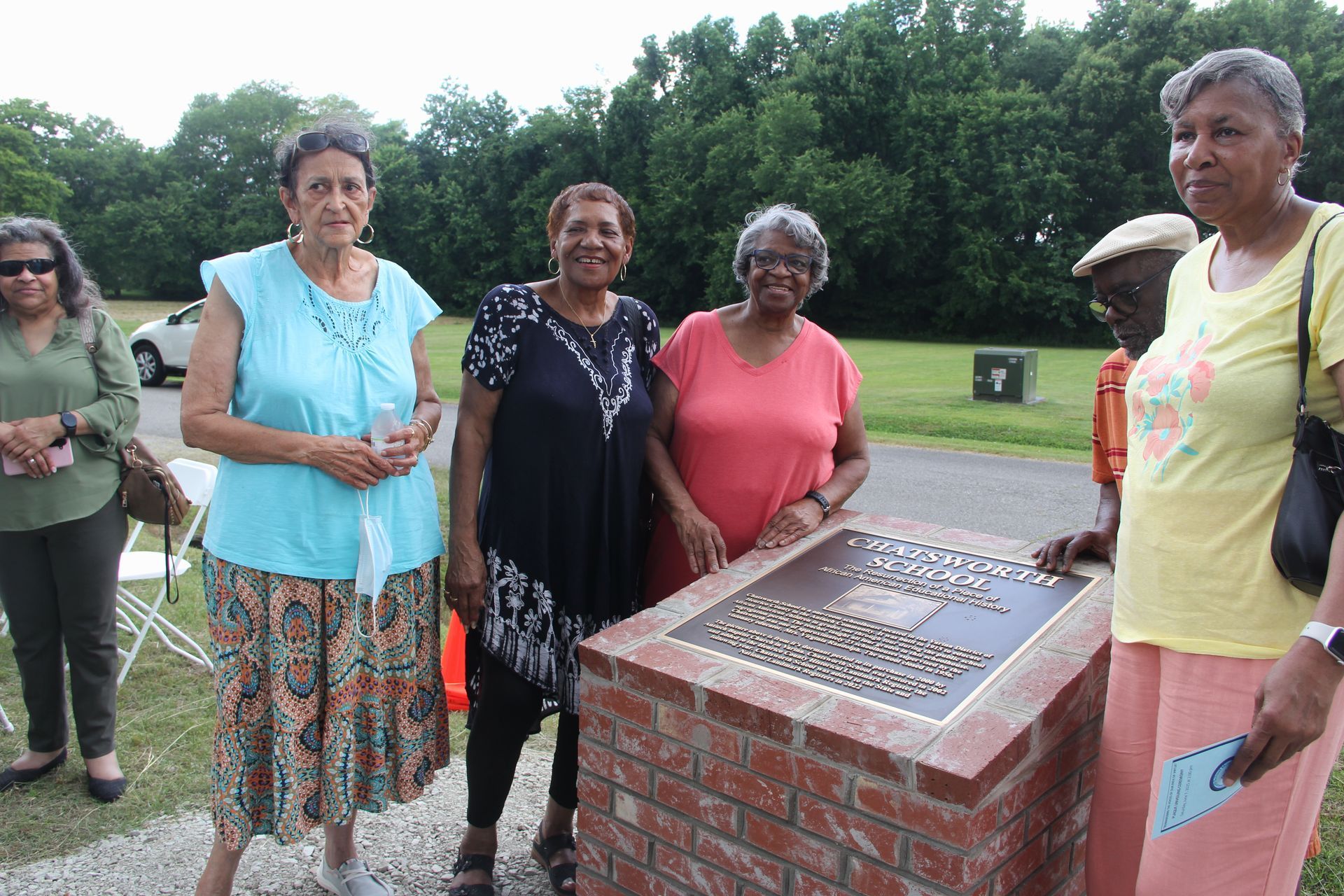 A group of women are standing around a brick plaque.