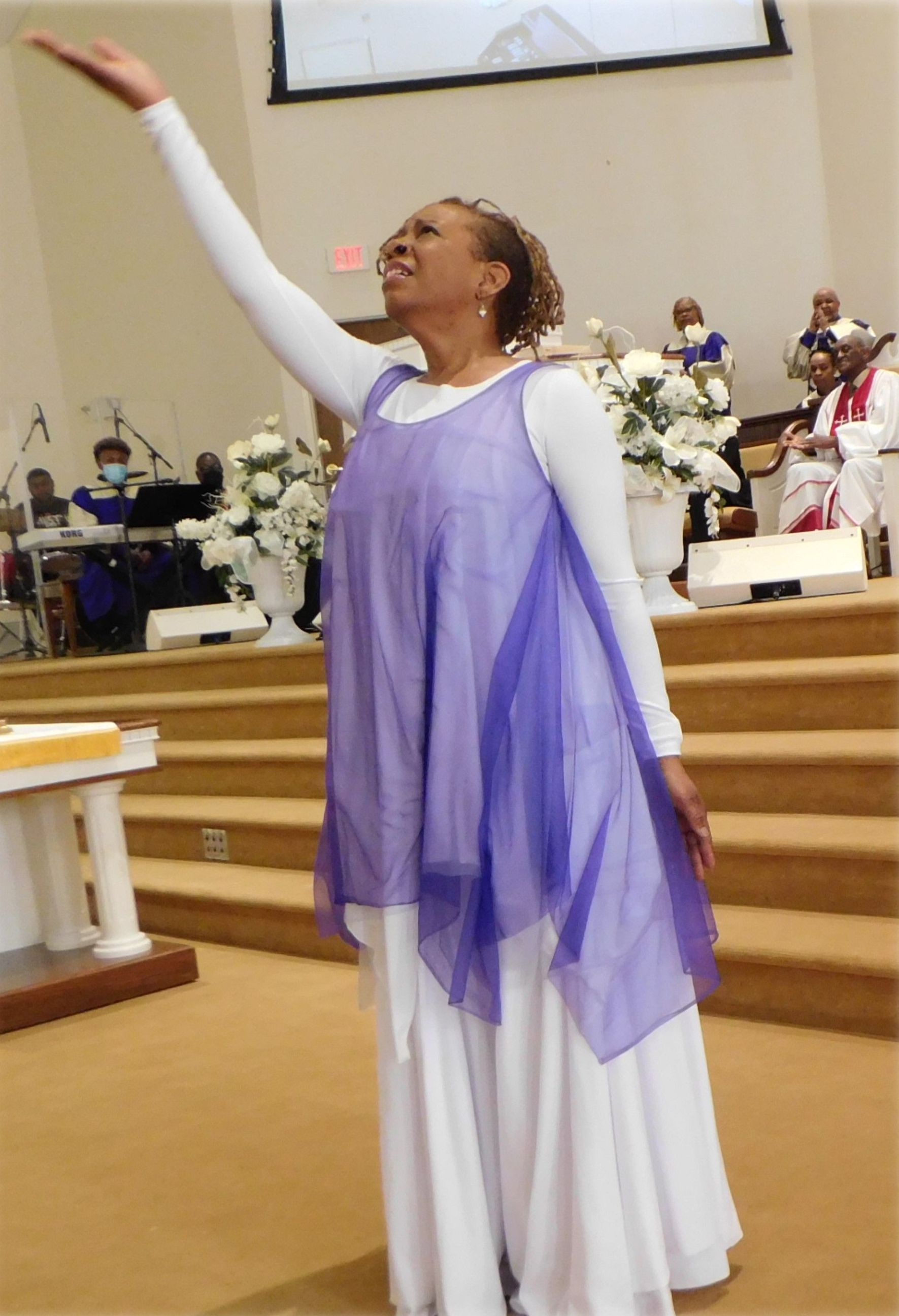 A woman in a purple and white dress is dancing in a church