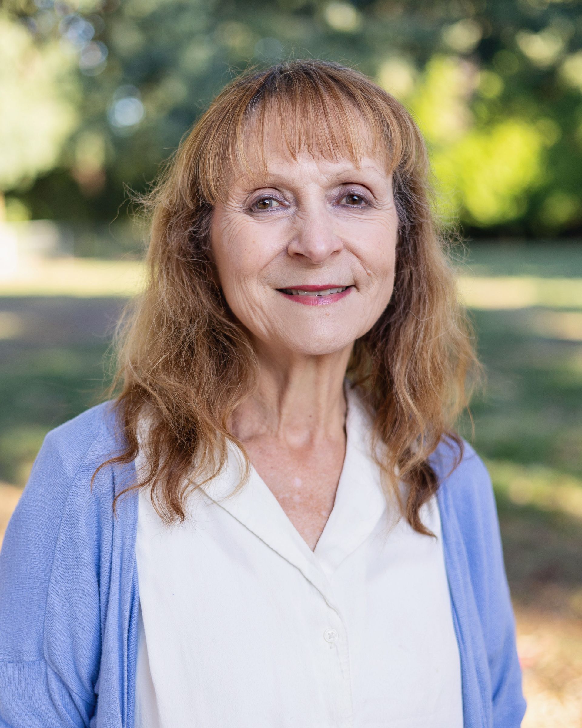 The woman is wearing a blue sweater and smiling for the camera.