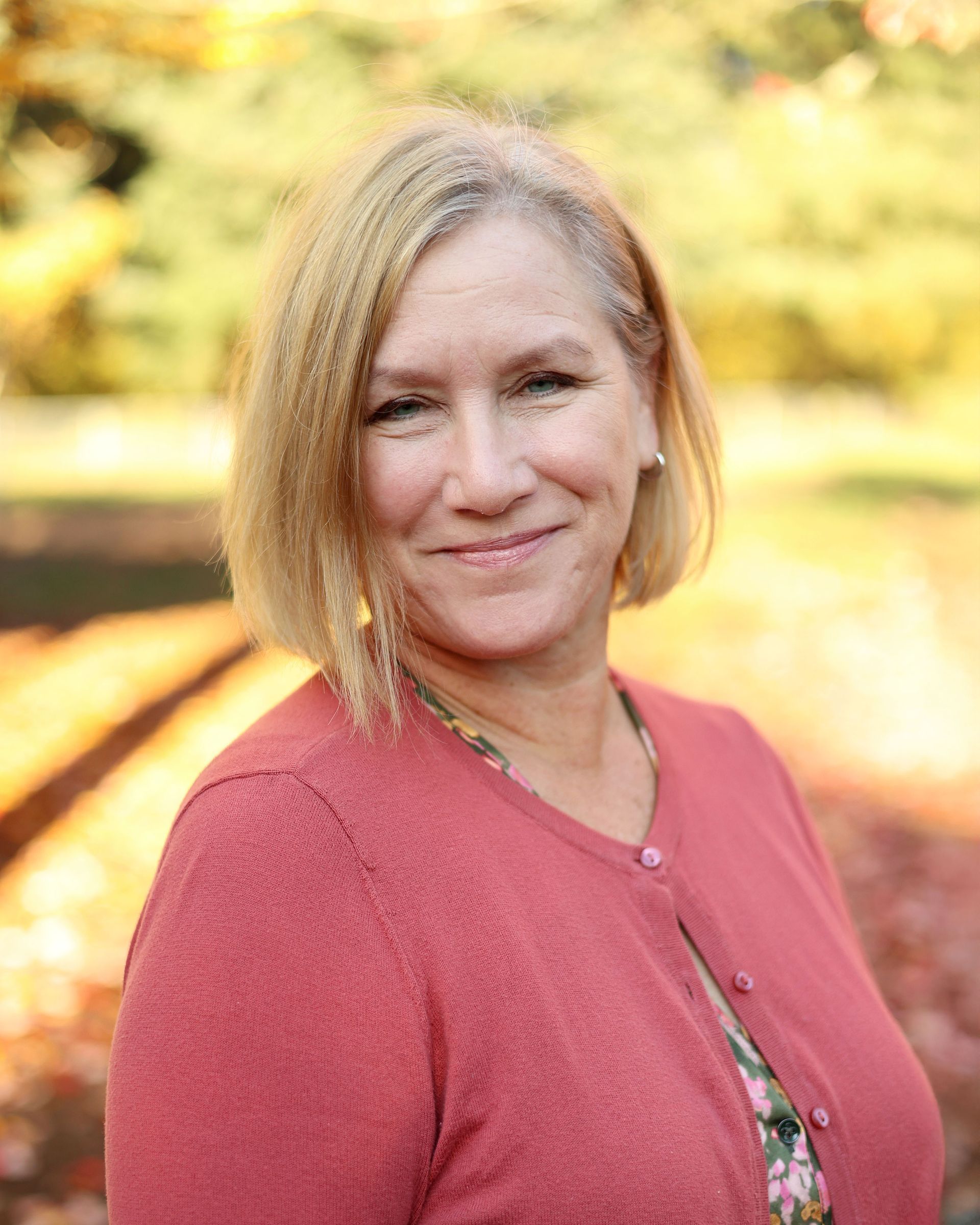 A woman in a blue sweater and leopard print shirt is smiling for the camera.