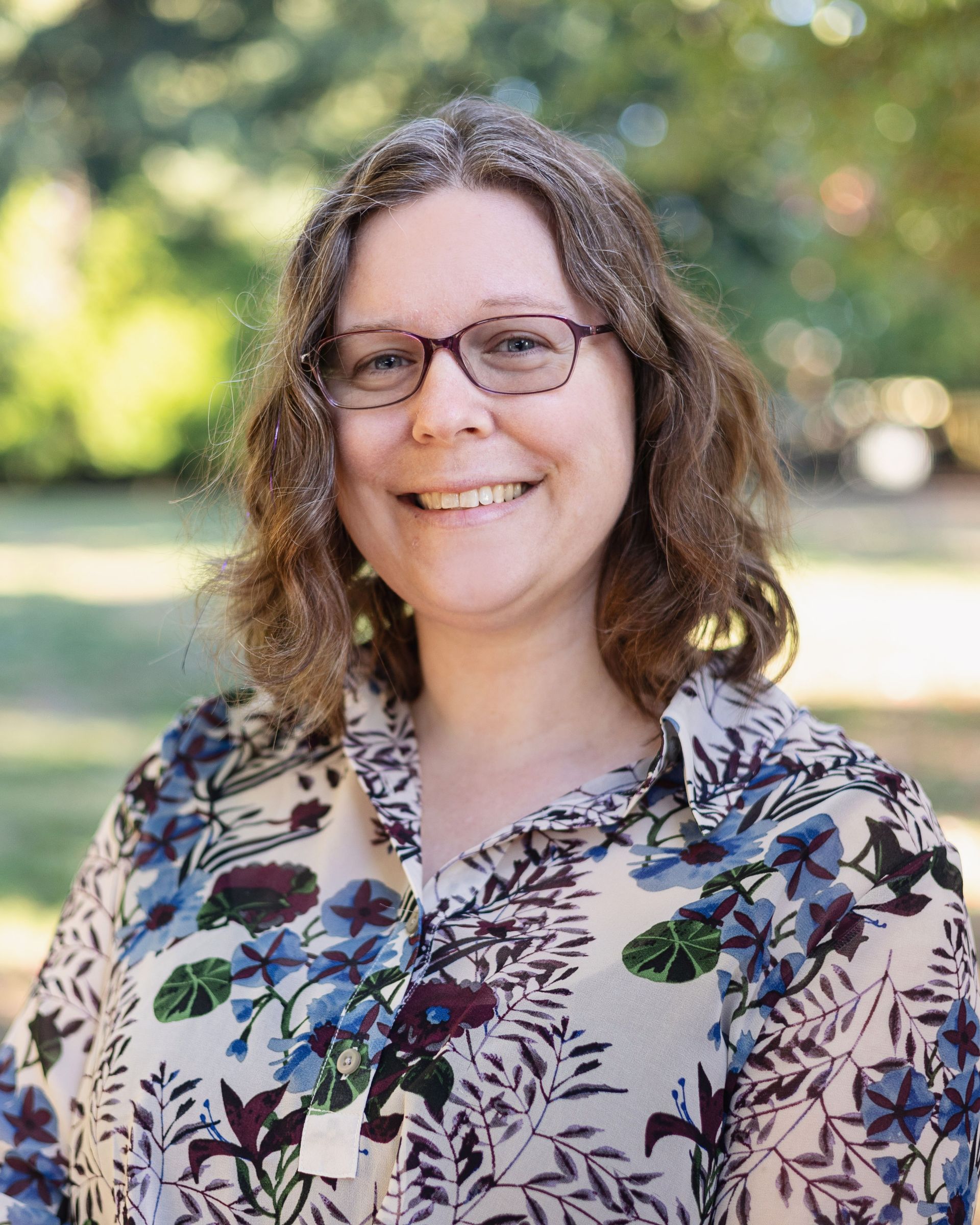 A woman wearing glasses and a striped shirt is smiling for the camera.