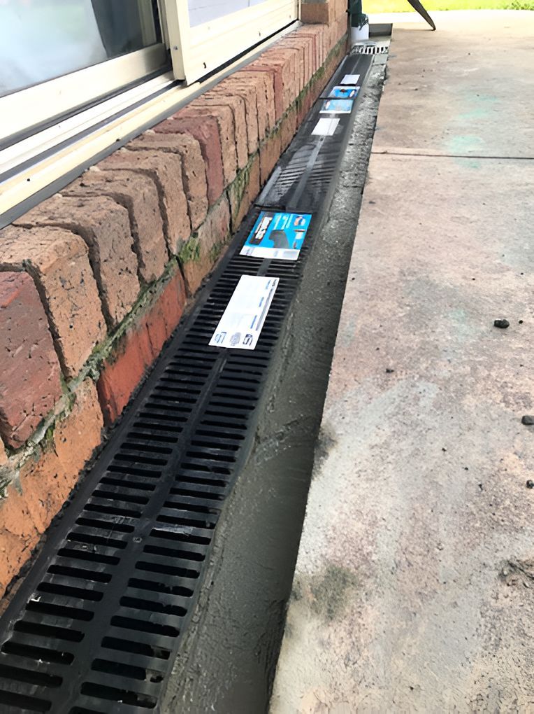 A Drain On The Side Of A Brick Building Next To A Window — DJ McLean Plumbing in Bonnells Bay, NSW