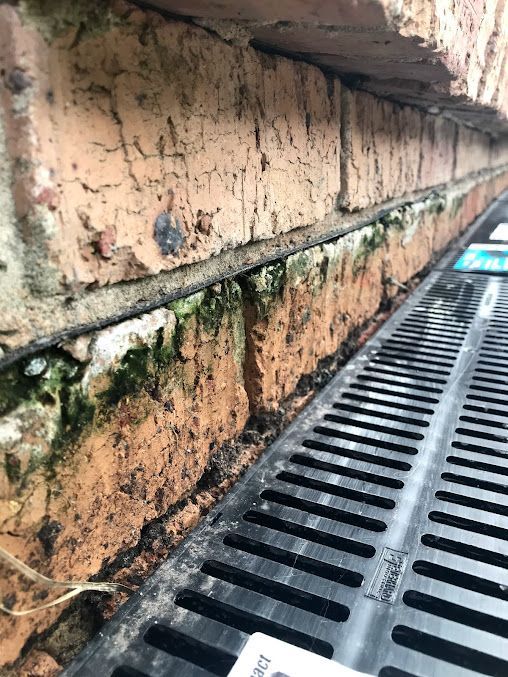 A Close Up Of A Drain On A Brick Wall — DJ McLean Plumbing in Bonnells Bay, NSW